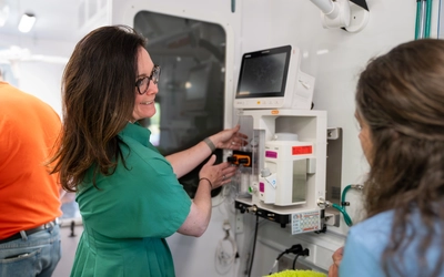 A dean and researcher examines new equipment inside a mobile veterinary clinic.