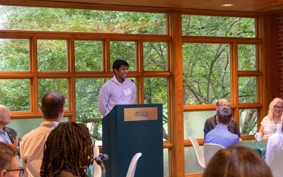Aaron Philip speaking at a podium to a room of people.
