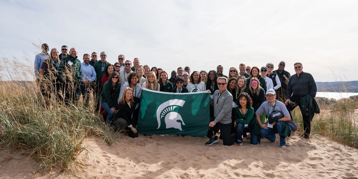 Group of people on a beach with a Spartan flag.