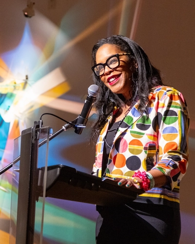Dr. Ruth Nicole Brown speaks at a podium at the exhibit opening at the Flint Institute of Arts.