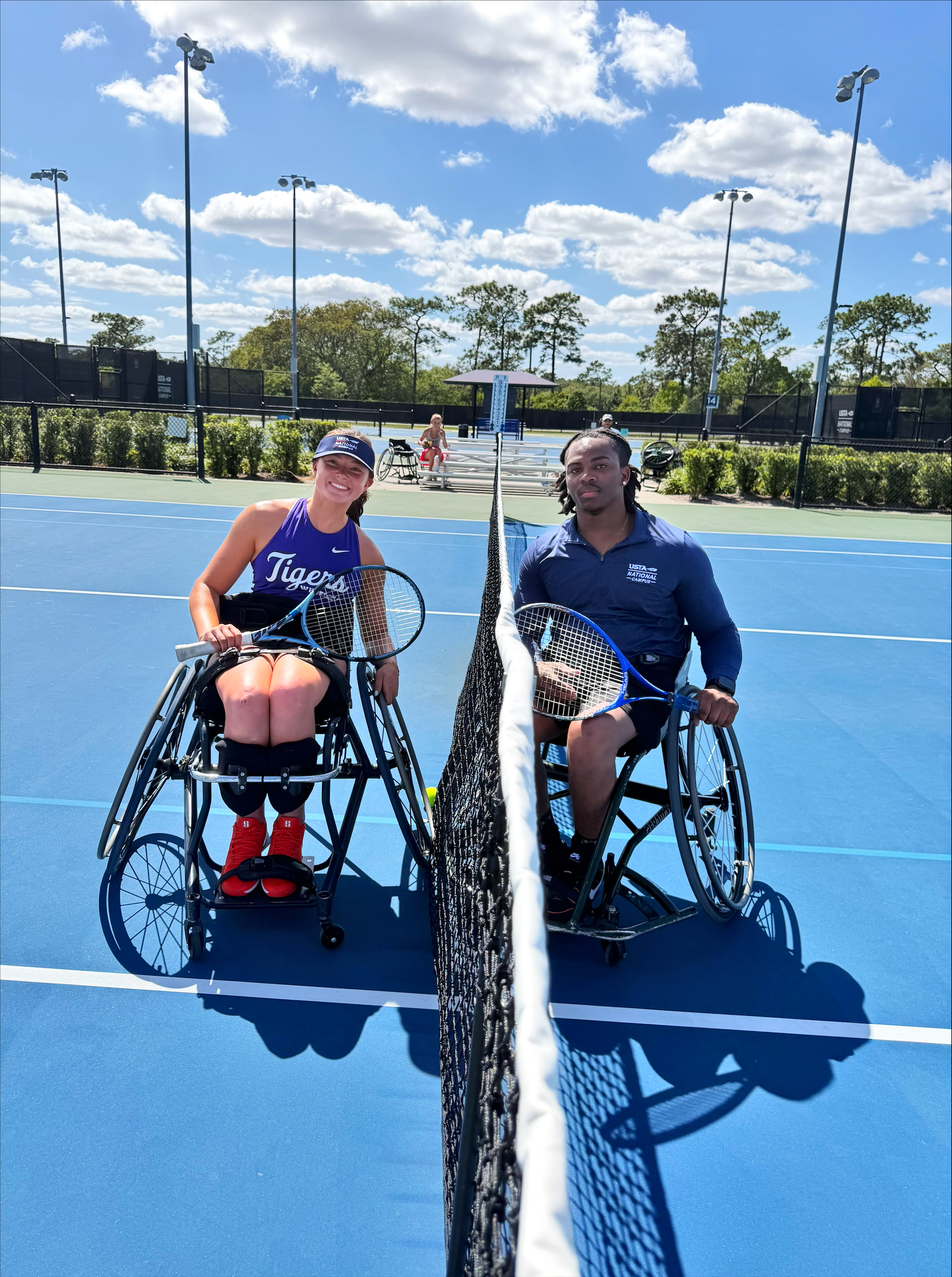 a man and woman in adaptive wheelchairs on a tennis court holding rackets