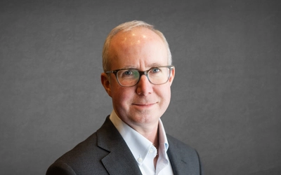 Headshot of Eric Nordman in a grey suit with a grey background.