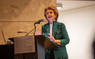 Debbie Stabenow stands at a lecturn and speaks into a microphone in an auditorium.