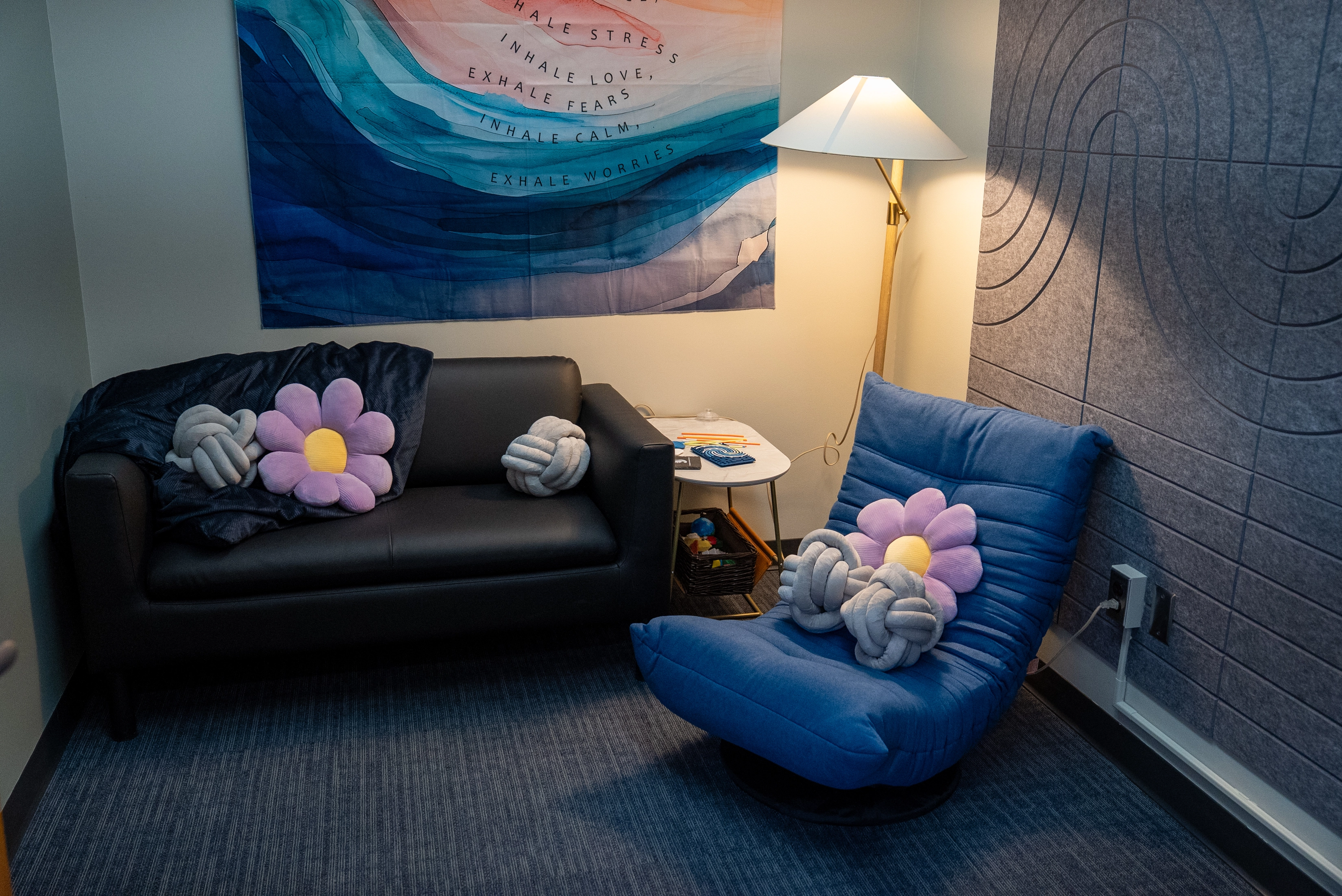 sensory room with a couch, chair, pillows, blanket, and warm lighting