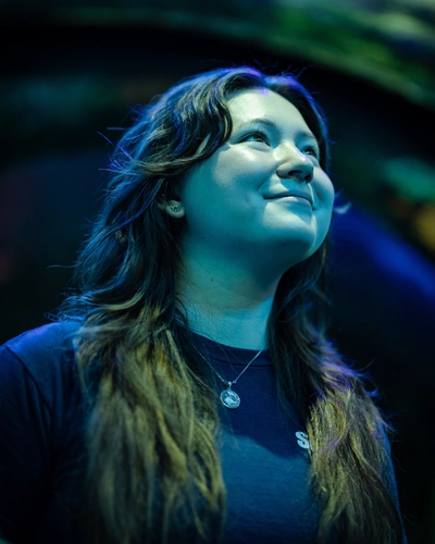 Dana MacCallumMhor poses for a portrait with a bluish glow from an aquarium