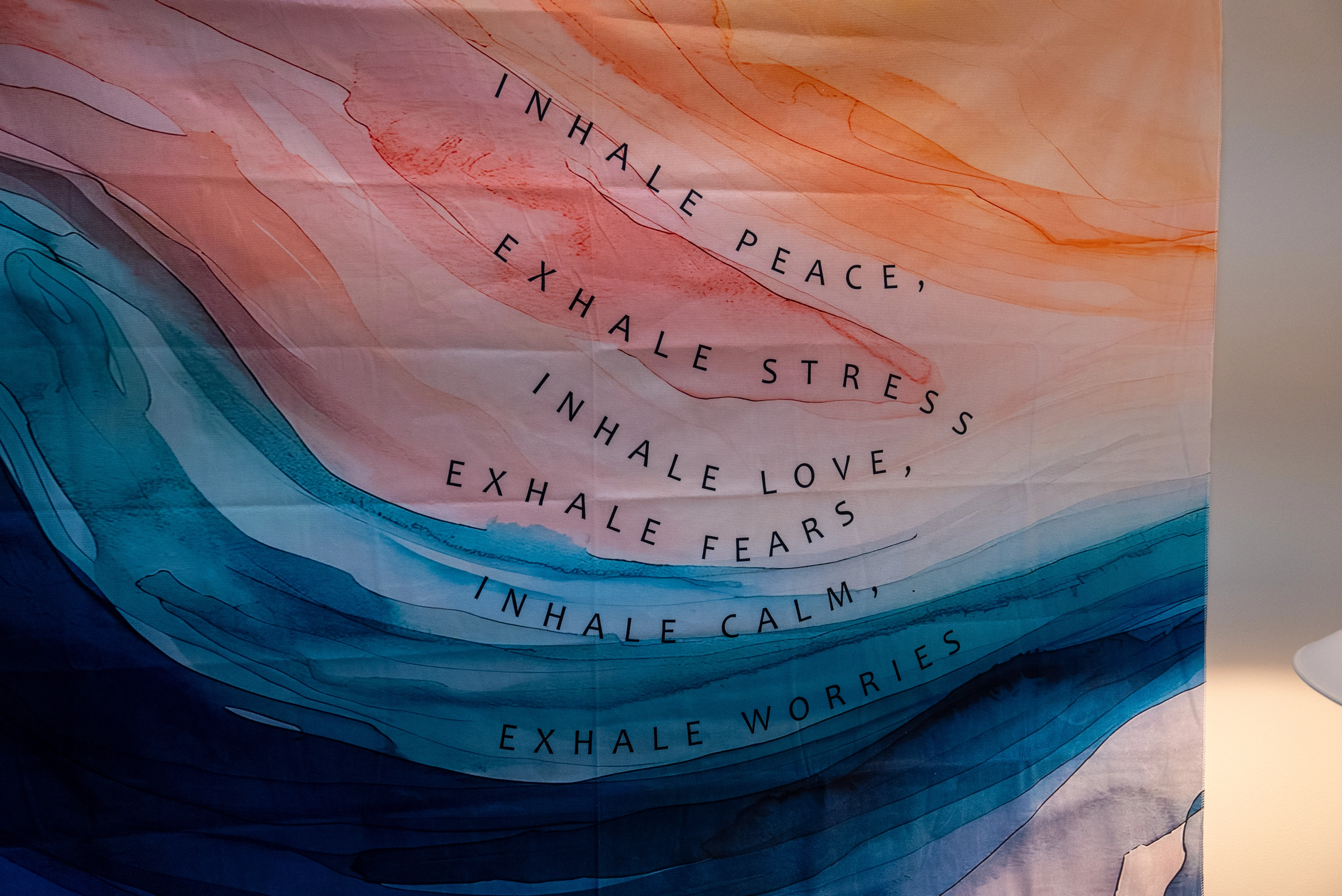 Wall art in pastel topographic patterns with the words inhale peace, exhale stress, inhale love, exhale fears