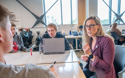 Laura Lee McIntyre chats with students around a table in the STEM Teaching and Learning Facility