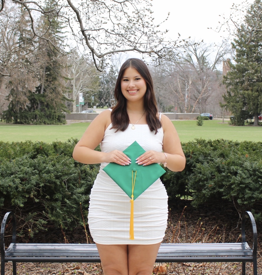 a student holds a green graduation cap
