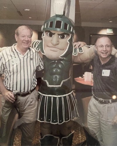 Gerald Fisher (right) with his law partner and the Sparty mascot at a varsity alumni golf outing.