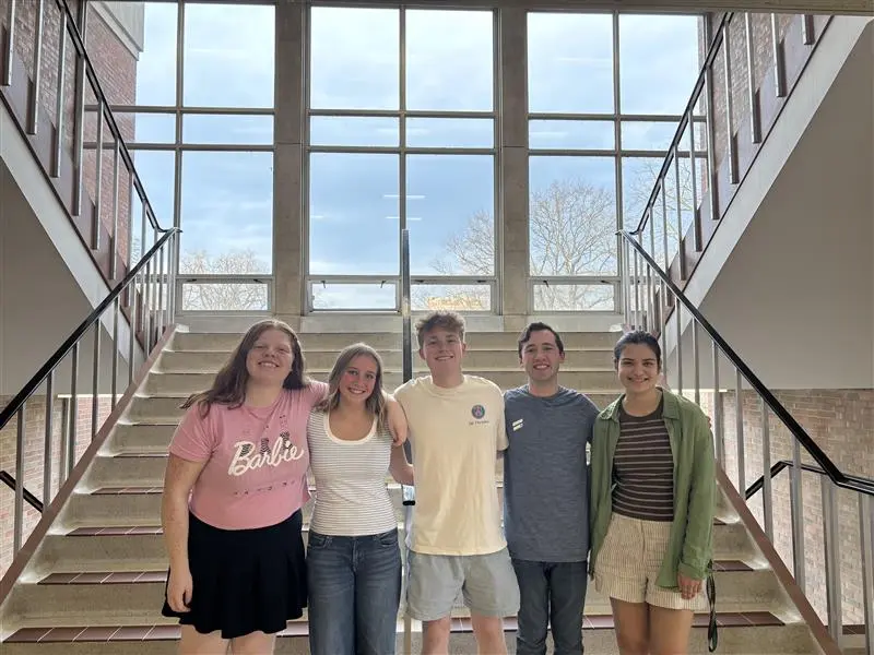 A group of students arm in arm in a staircase
