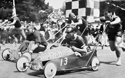 Image of a Push Race with a man sitting in the cart and somebody pushing it.