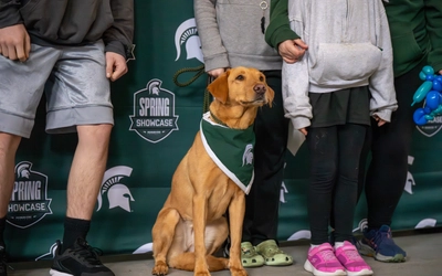Zeke wearing a Spartan bandana sits in front of a Spring Showcase backdrop.