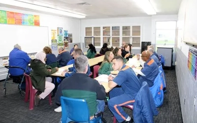 Image of a classroom with two long tables filled with people discussing with each other.