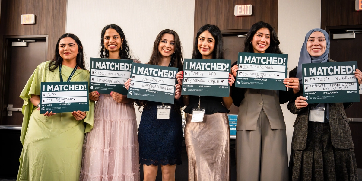 Six female medical students standing in a row holding green "I MATCHED!" signs.