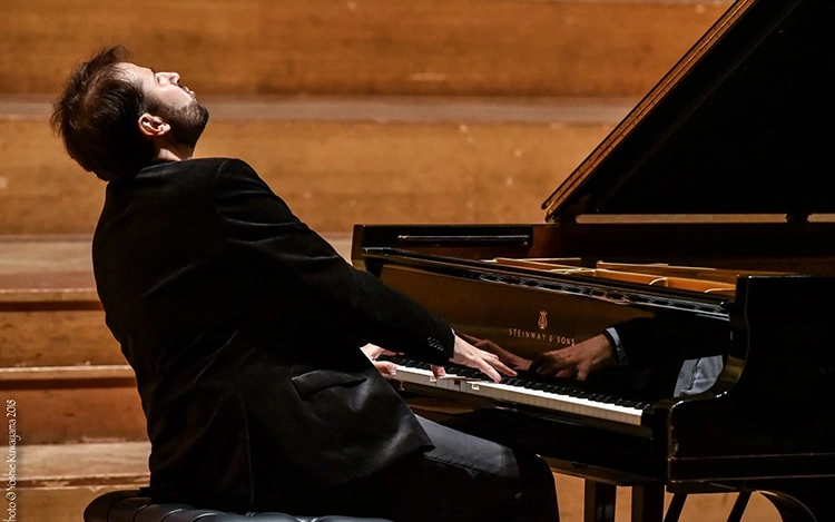 Pianist Stanislav Khristenko playing a Steinway grand piano on stage during a performance.