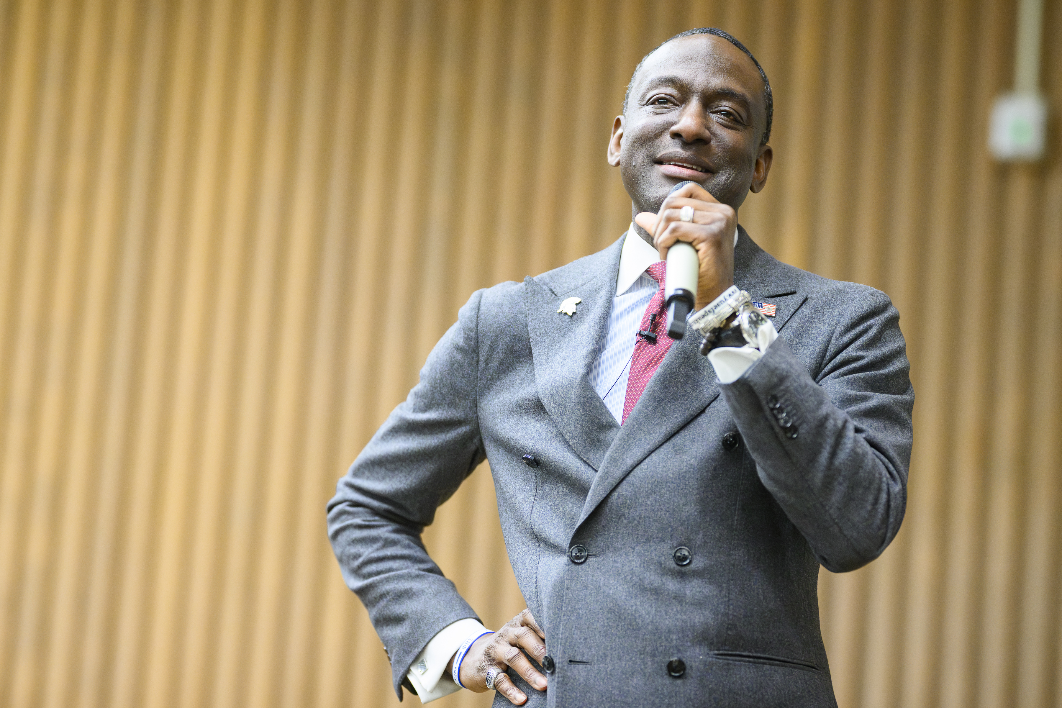 A man in a suit speaks confidently into a microphone