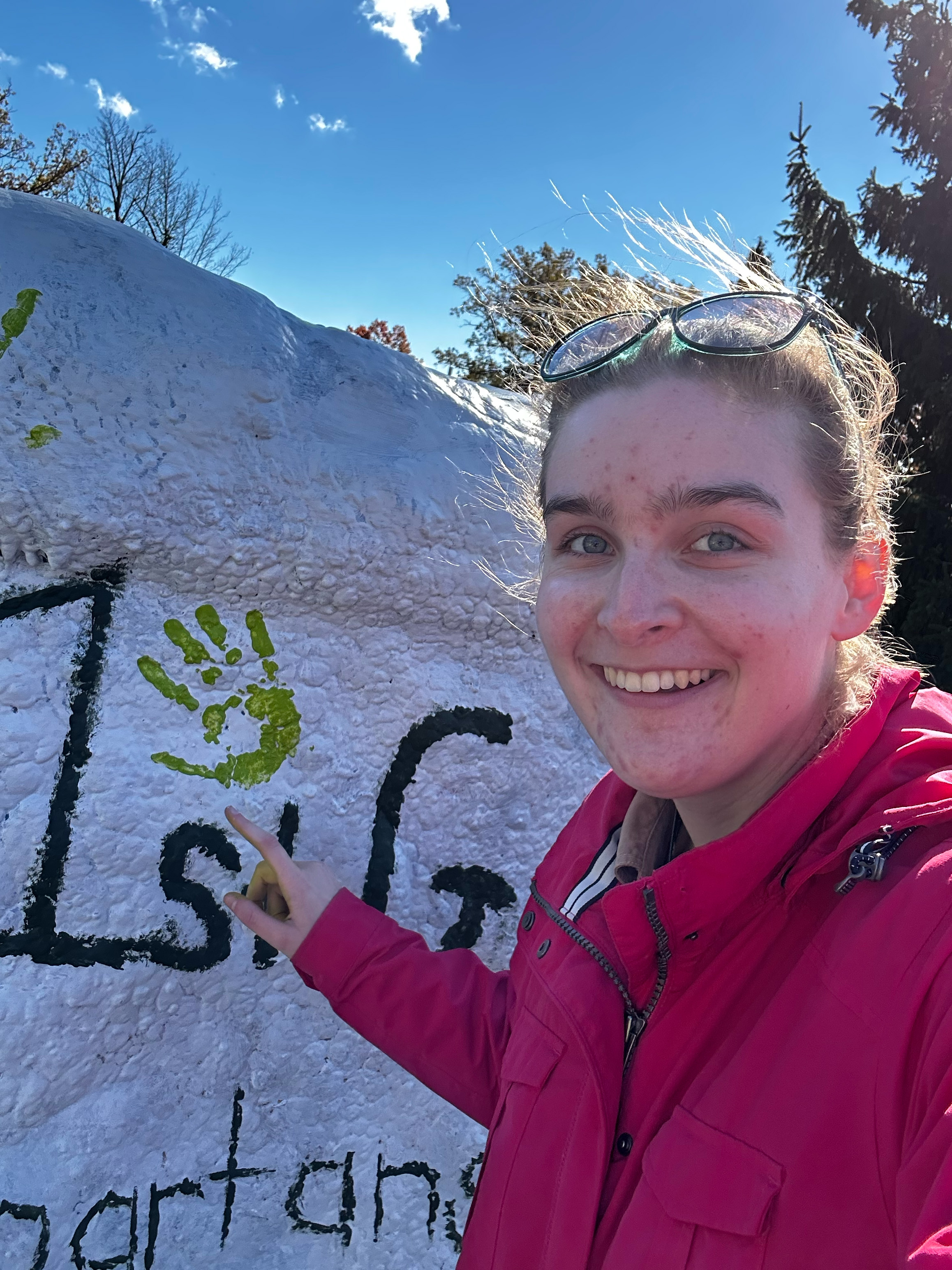 A woman smiles and points to the word 1st painted on a rock