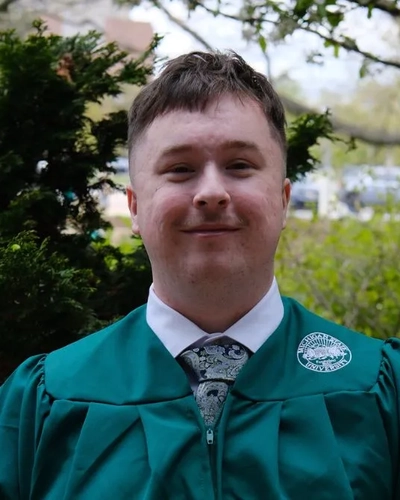 A portrait of Liam McDonald smiling in MSU's graduation regalia.