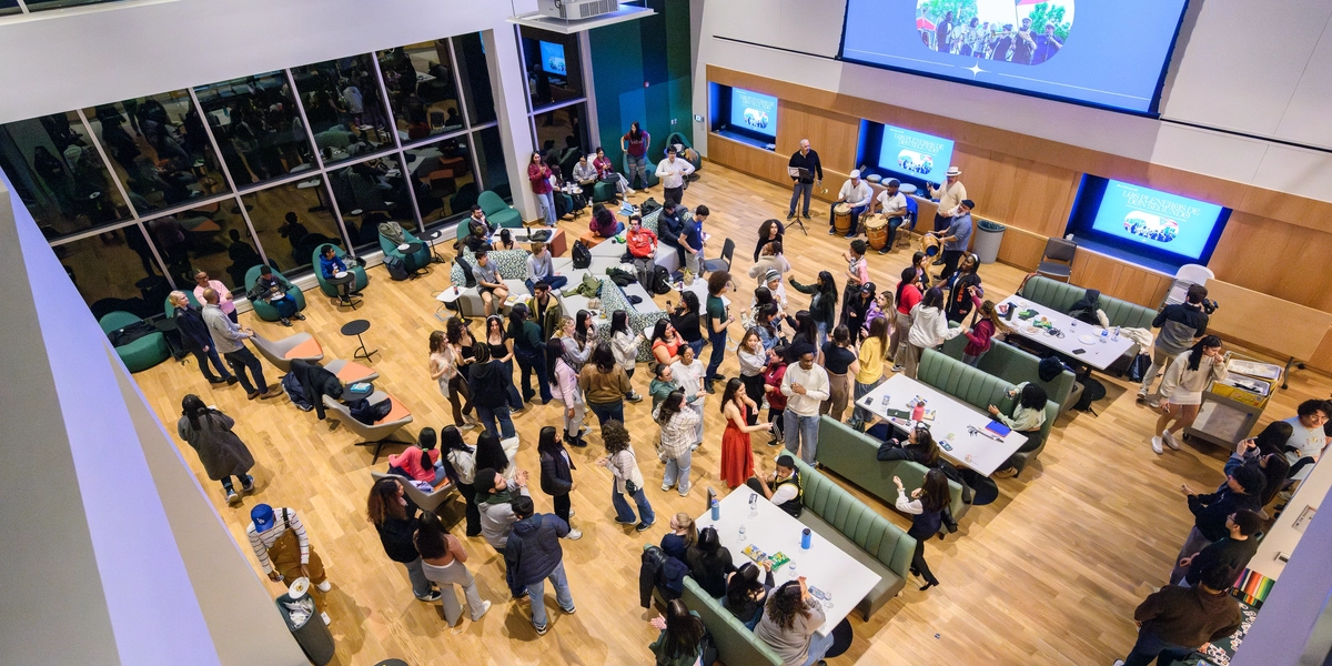 Overhead of the living room open area in a building with people standing throughout the floor