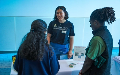 Jade McLellan speaks with attendees while showcasing custom cookies from Baking By Jade at a Michigan State entrepreneurship event.