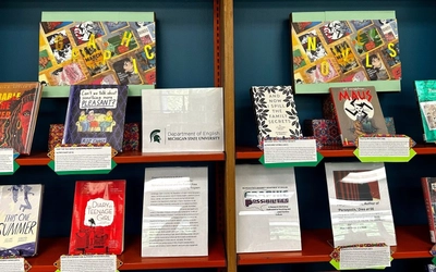 A display of books on a shelf, each with a description plaque in front of them.