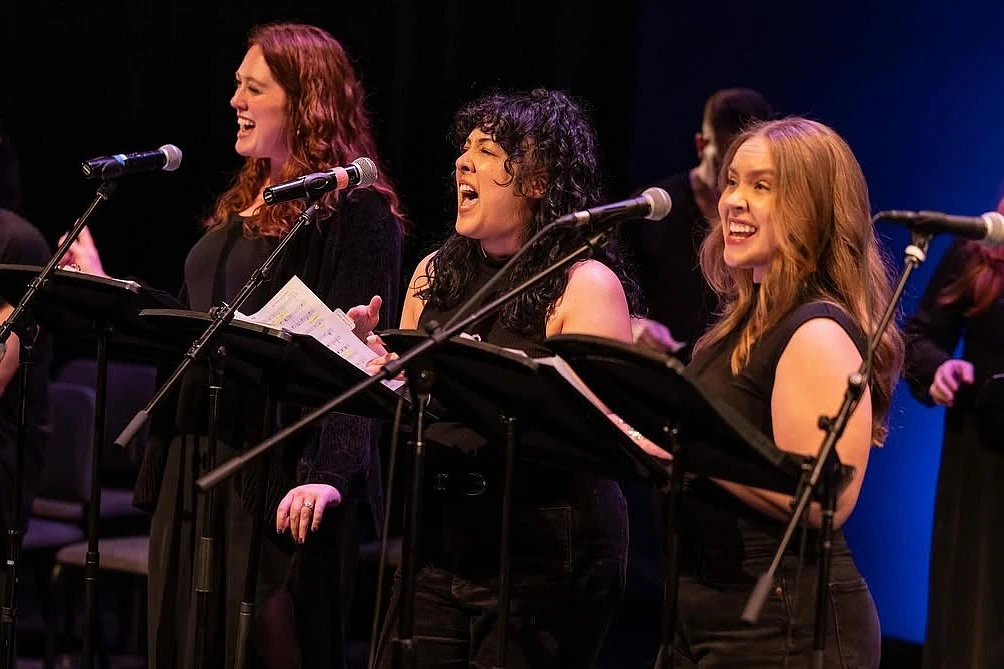 Three singers performing onstage.