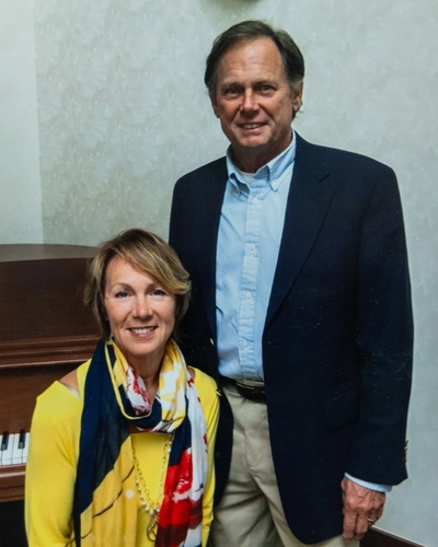 MSU Alum Kirk Faber on the right stands next to wife, Celeste, seated at a piano.