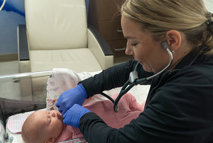 Stacy Volkers listening to a baby's heart with a stethoscope.