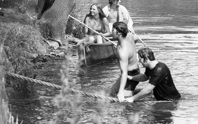 Four students on the bank of the Red Cedar pulling ropes while participating in tug-of-war.