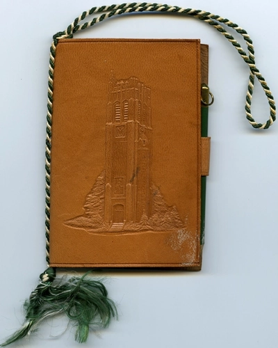 A dance Card for the 1946 J-Hop presented by the class of 1947. The dance card lists the class officers, committee chairmen, patrons and patronesses, and guests. The cover is made of leather with an impression of Beaumont Tower. The back cover has a pad of paper attached to it and a leather loop for a pencil. There is a wrist loop of green and white satin cord attached looped through the spine of the dance card.