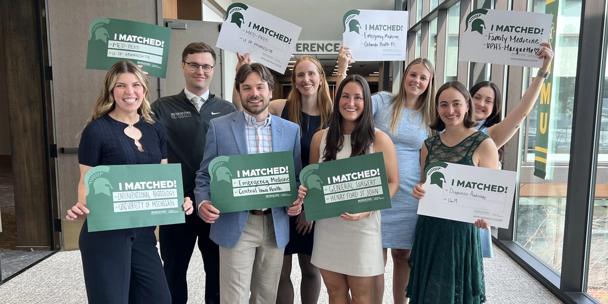 A group of eight medical students holding residency match signs at the Upper Peninsula campus.