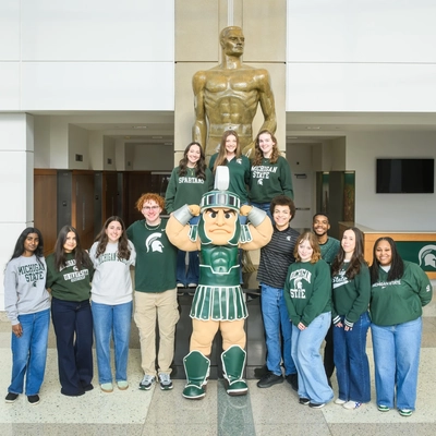 12 MSU students on the 2026 Homecoming Court pose in a group for a photo with Sparty.