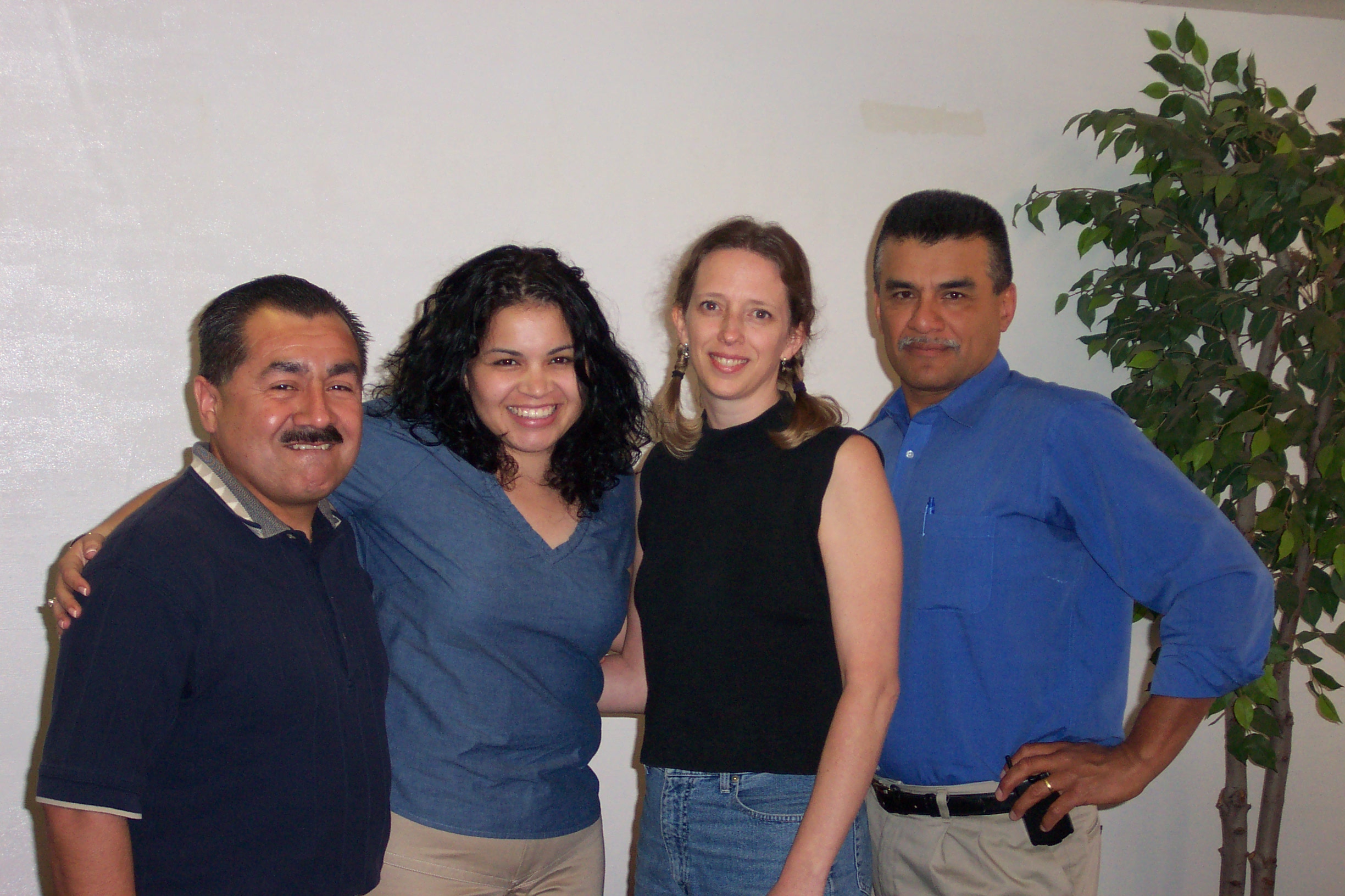 A group of office staff standing by a plant