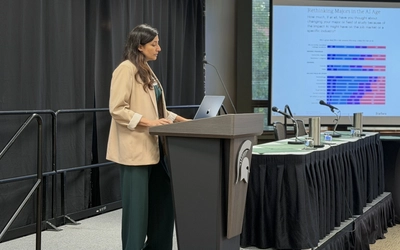 A researcher stands at a podium and gives a presentation to begin a conference.