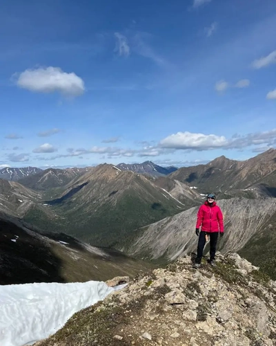 Katie Maloney standing among the Ogilvie Mountains, Yukon, as they span around her.
