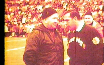 Screenshot image from video of the Spartan head coach Duffy Daugherty and Fighting Irish head coach Ara Parseghian on the football field. This picture is a still from a moving image film reel.
