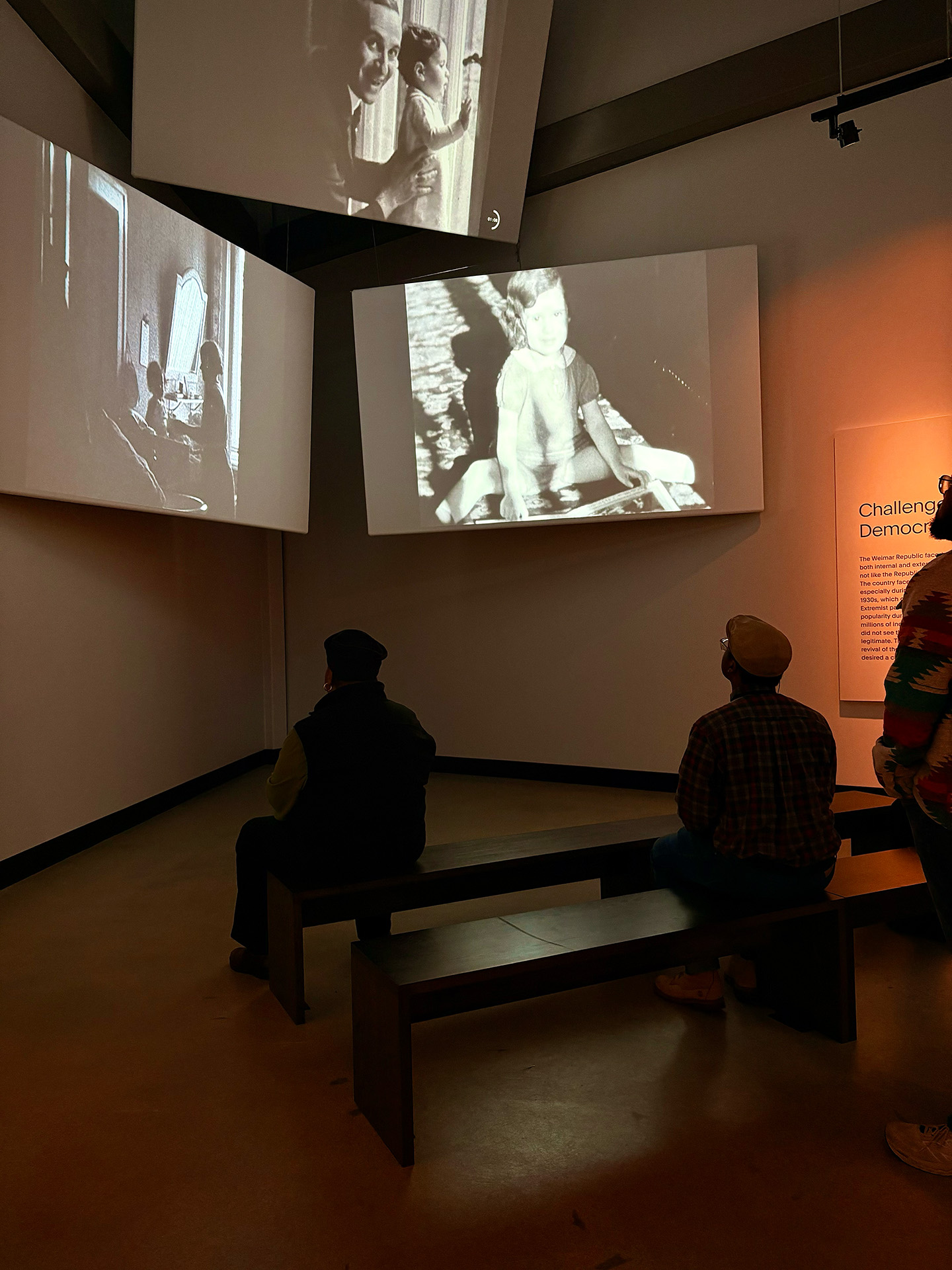 Silhouette participants observe projected photos on screens