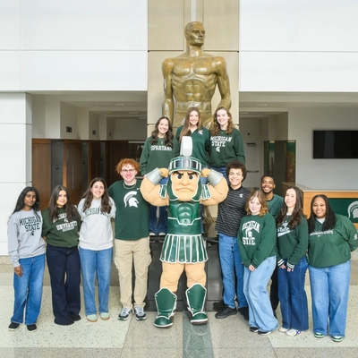 12 MSU students on the 2026 Homecoming Court pose in a group for a photo with Sparty.