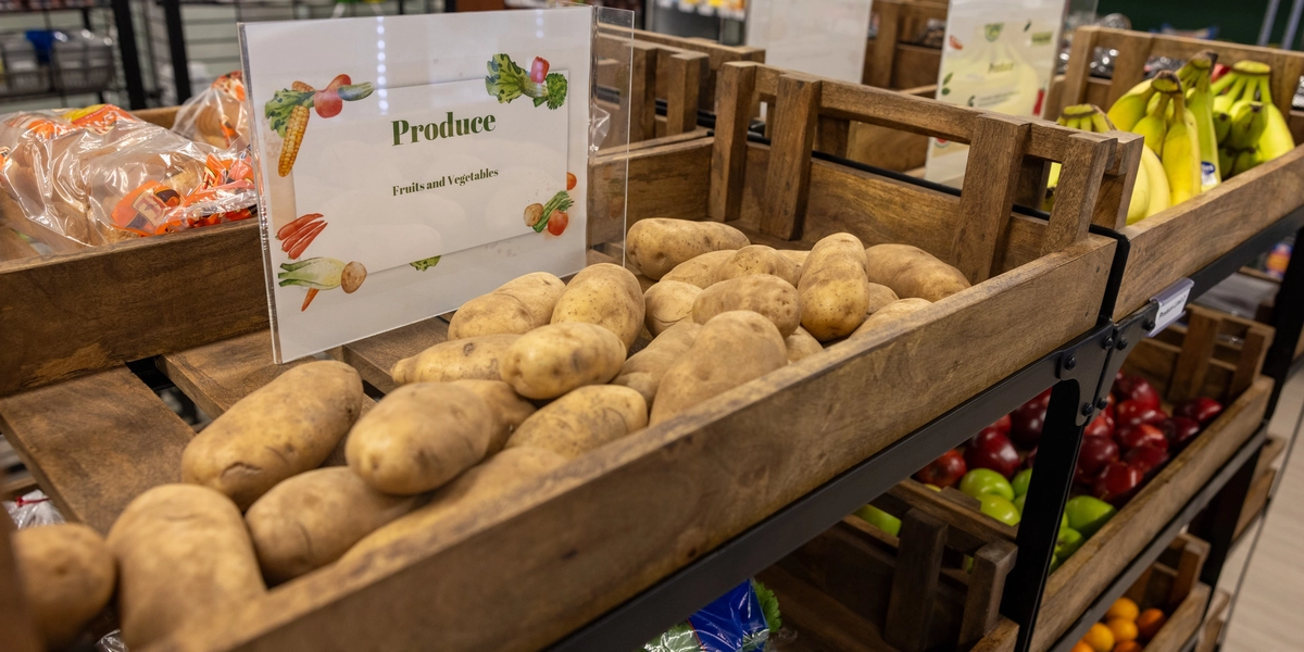 A close-up of potatoes under a sign titled "produce" inside the Spartan Shelf