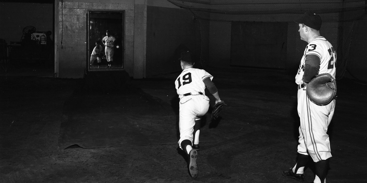MSU Baseball player watches another player throw at the Unbreakable Mirror to review his pitching form. The ball is heading toward the mirror in this image.