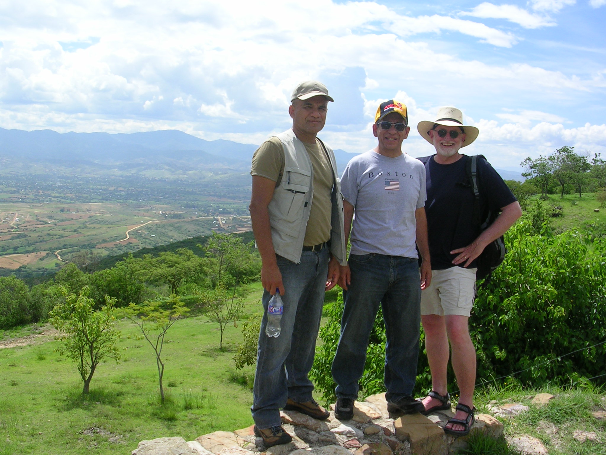 Three men standing in a rural scenic area