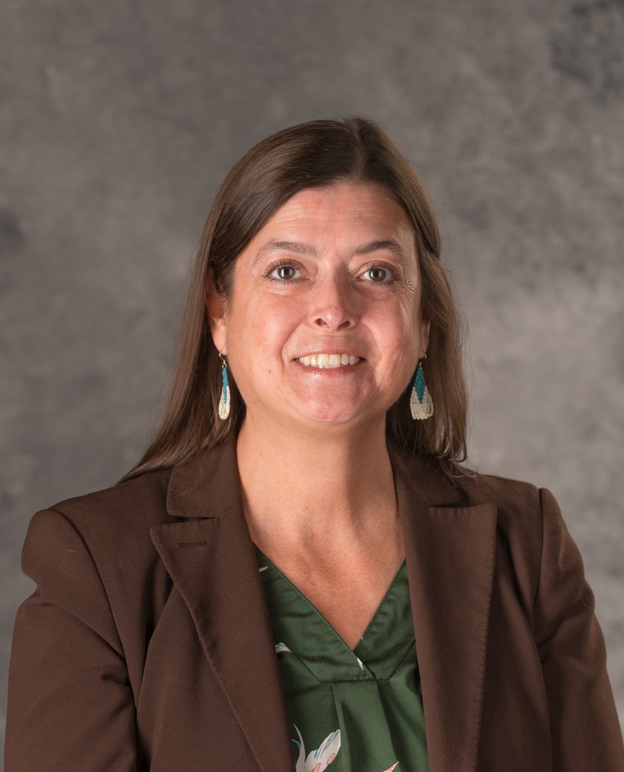portrait of woman in brown blazer and green top