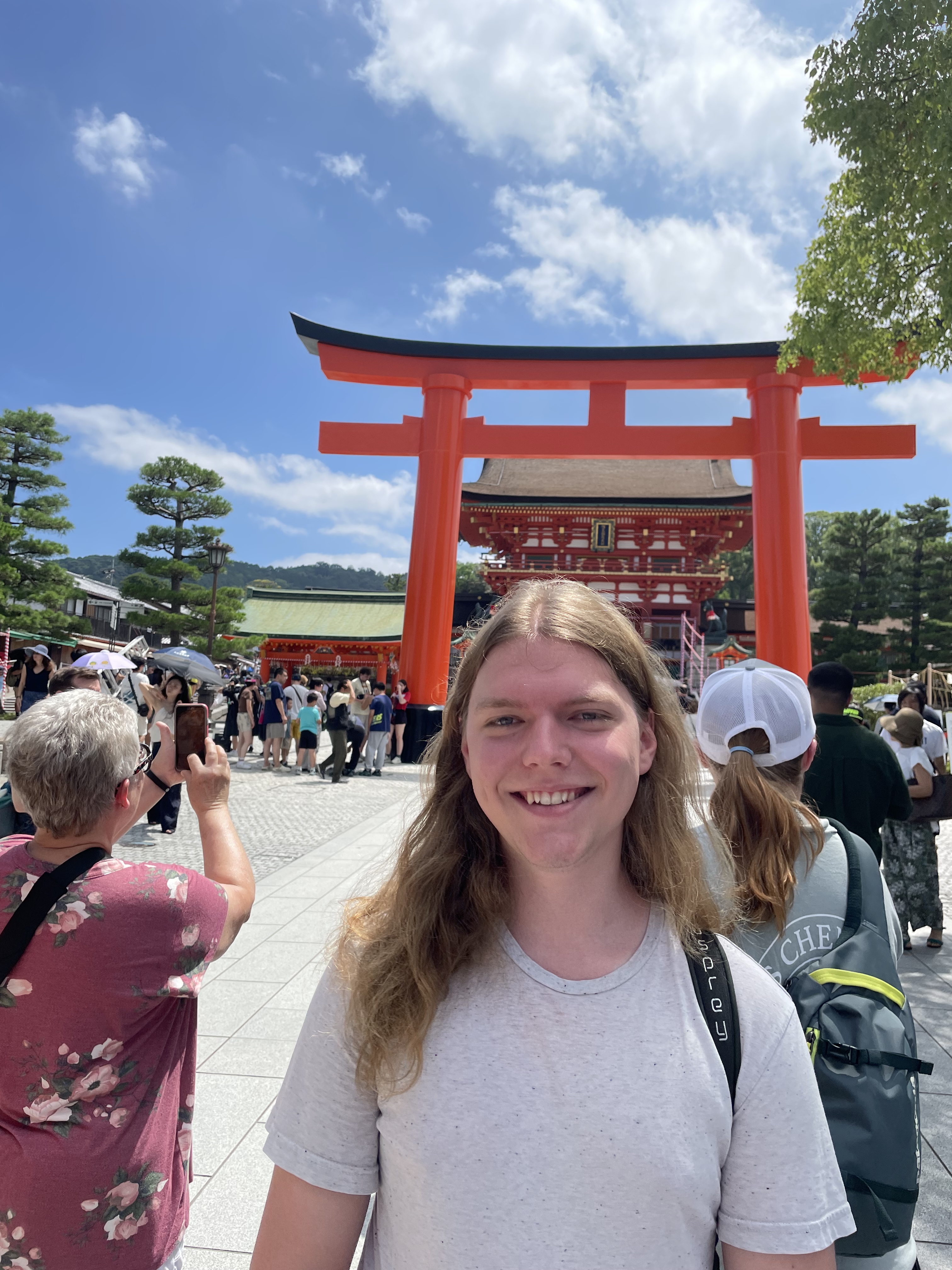 A person poses in front of torii gate