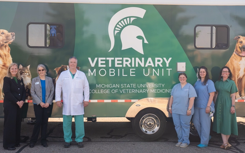 Professors and officials at MSU stand outside in front of a new clinic on wheels that can travel to care for pets.