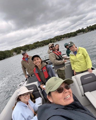 A group of eight people pose on a boat in a lake for a selfie
