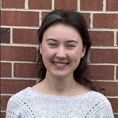 Woman standing in front of a brick wall.