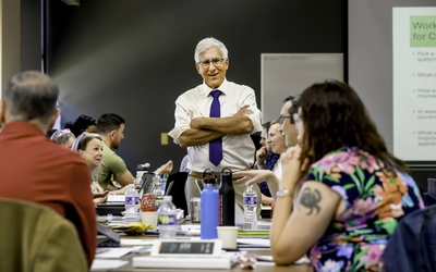 A workshop facilitator smiling with arms crossed during a session part of Museum Leadership Academy.