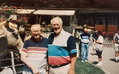 Henry Nelson poses with Ken Bloomquist in an outdoor setting with other people in the background