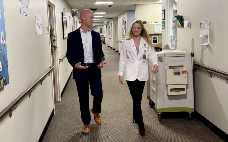 Kaylin Burton and Curt Gritters walk down an indoor hallway at Holland Home Raybrook Campus.