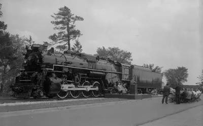 A stationary steam train with onlookers.